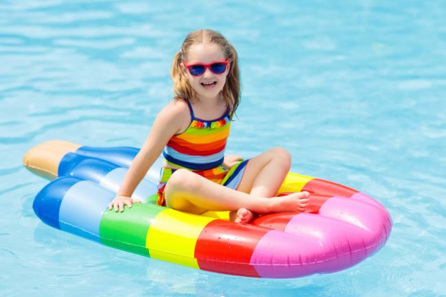 Child on inflatable pool floats in swimming pool. Child on pool floats toy